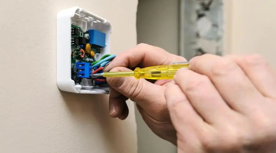 Close-up of a hand adjusting a thermostat during HVAC installation at Hancock & Son Plumbing, Heating and Air Conditioning.