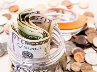 Jar filled with rolled cash and assorted coins, representing savings and cost-effective solutions related to water heater replacement.