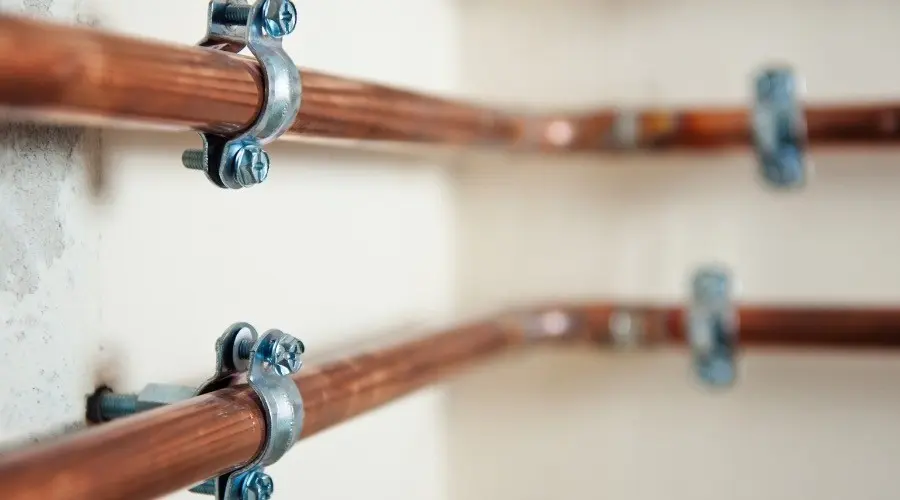 Copper pipes and clamps illustrating household water pressure issues and plumbing repairs.