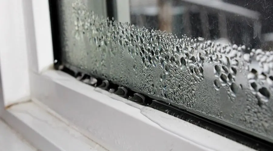 Condensation on a window pane, highlighting moisture beads in a cozy indoor setting, relevant to HVAC maintenance topics.