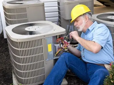 HVAC technician performing maintenance on air conditioning unit, ensuring efficiency and preventing future repairs.