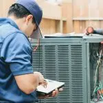 HVAC technician using a tablet for air conditioning maintenance, with tools and an outdoor background in Niles, MI.