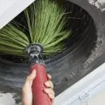 Hand holding a tire brush cleaning a rugged tire for HVAC maintenance at Jerry Brittingham A/C & Heat, Inc.