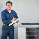 A man in a blue work uniform with a clipboard, showcasing HVAC maintenance expertise at Jerry Brittingham A/C & Heat, Inc.