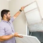 Man holding a dirty air filter in a home, emphasizing HVAC maintenance by Jerry Brittingham A/C & Heat, Inc.