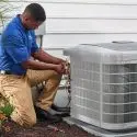 HVAC technician in blue uniform servicing an air conditioning unit outdoors for Jerry Brittingham A/C & Heat, Inc.