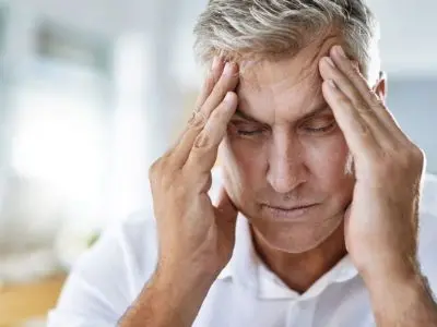 Middle-aged man experiencing headache and stress, illustrating health effects of poor indoor air quality, relevant to HVAC maintenance and wellness.