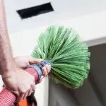 Bright green duster held by hands indoors, used for cleanliness in homes&mdash;Jerry Brittingham A/C & Heat, Inc.