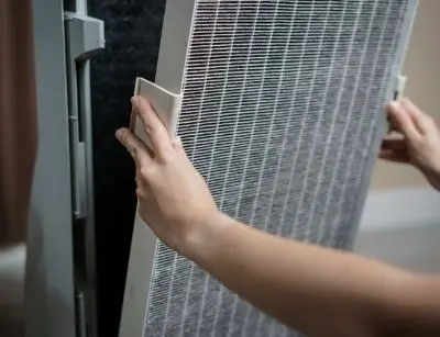 Person inserting a HEPA filter into an air purifier, demonstrating maintenance for improved indoor air quality and allergy management.