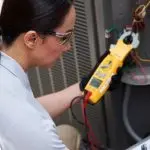Female technician with multimeter working on electrical panel; HVAC service by Jerry Brittingham A/C & Heat.