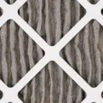 Worn air filter with pleated paper texture, emphasizing indoor air quality maintenance for HVAC systems.