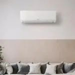 Air conditioning unit and modern couch in a contemporary living space by Jerry Brittingham A/C & Heat, Inc.