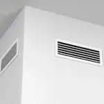 Minimalist corner of a room with air vents, showcasing clean lines and a white wall for efficient HVAC system maintenance.
