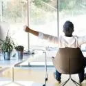 Person in a modern chair surrounded by indoor plants and large windows, highlighting an open space related to HVAC services.