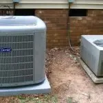 Two air conditioning units by Jerry Brittingham A/C & Heat, Inc., with a Carrier unit on a concrete base in a grassy area.
