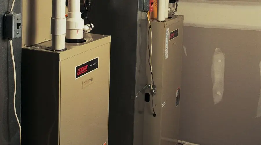 Metal heating units with pipes and controls in a garage by Jerry Brittingham A/C & Heat, Inc. for HVAC services.