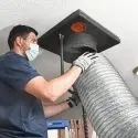 A man in gloves and a mask servicing ductwork, highlighting HVAC maintenance for Jerry Brittingham A/C & Heat, Inc.