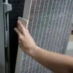 Hand replacing a textured air filter in an air conditioning unit for better air quality by Jerry Brittingham A/C & Heat.