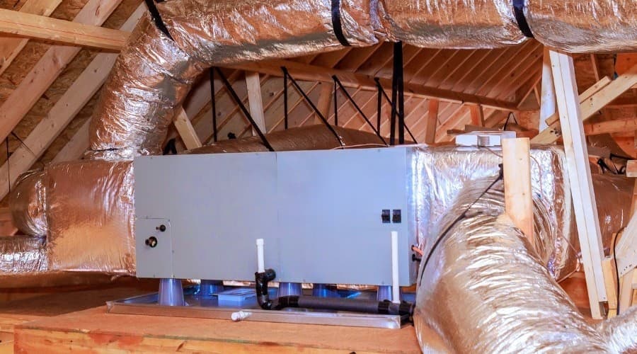 Air handler unit and ductwork in attic illustrating HVAC system components.