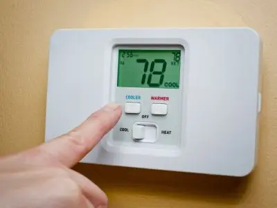 Thermostat displaying 78&deg;F with a hand adjusting the temperature settings, illustrating signs of inconsistent temperature readings and potential HVAC issues.