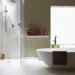 Modern bathroom featuring a freestanding bathtub, glass shower, and natural light, illustrating efficient water use and plumbing design.