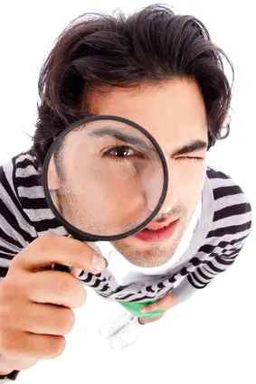 Man inspecting a water heater with a magnifying glass, emphasizing the importance of identifying repair or replacement needs for home plumbing systems.