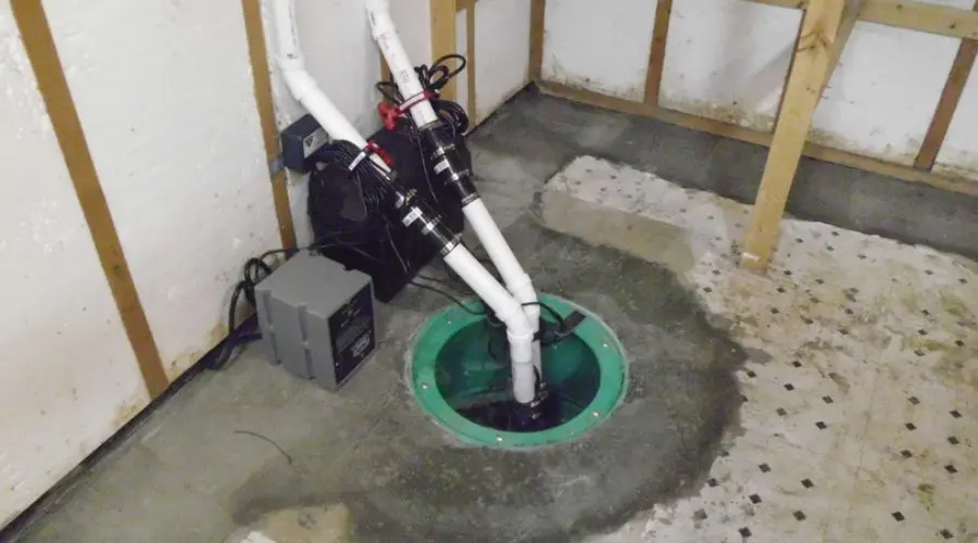 Sump pump installation in a basement with connected pipes and electrical components, highlighting plumbing solutions for homeowners.