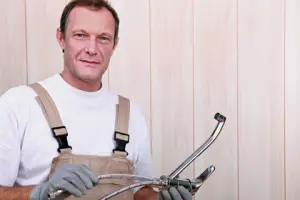 Plumber holding plumbing tools, emphasizing professional expertise in plumbing maintenance and repair services.