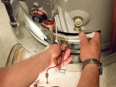 Plumber performing routine maintenance on a water heater, inspecting and adjusting components to enhance energy efficiency and reliability.