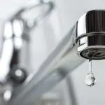 Dripping faucet with water droplet, highlighting potential plumbing leak detection issues for homeowners.