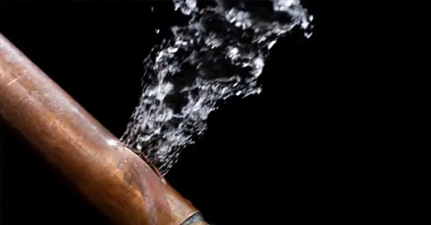 Burst copper pipe spraying water, illustrating urgent plumbing repair needs for burst pipe services by The Plumbing Dr.