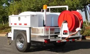 Hydro jetting service trailer with water tank and hose reel, used for effective sewer line cleaning and maintenance.