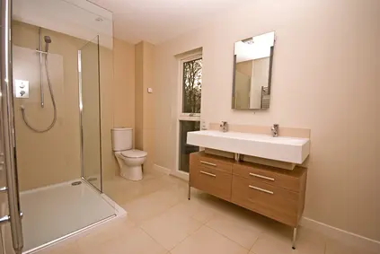 Depositphotos_1935302_xs Modern bathroom featuring a glass shower, dual sink vanity, and neutral-toned decor, illustrating a new shower installation for home plumbing services.