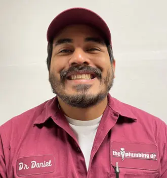 Dr. Daniel, plumbing technician at The Plumbing Dr, smiling in work uniform, showcasing expertise in customer service and plumbing skills.