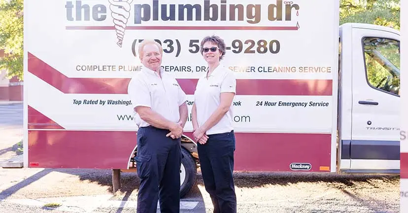 Two professional plumbers standing in front of a branded service van from The Plumbing Dr, showcasing contact information and service offerings for residential plumbing and emergency support in Arlington, VA.