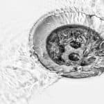 Drain with water flowing around it, illustrating effective hydro jetting for professional plumbing services and drain cleaning.