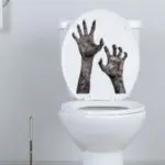 Halloween-themed toilet seat cover featuring spooky hands reaching up, enhancing bathroom decor for a frightful atmosphere.