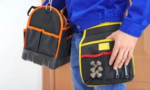 Plumber holding tool bags, showcasing essential plumbing tools for residential and industrial services.