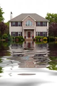 Flooded house with water surrounding the foundation, illustrating the need for sump pump installation and maintenance.