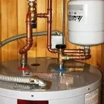 Water heater with copper pipes and anode rod, illustrating plumbing maintenance and corrosion prevention for extending appliance lifespan.