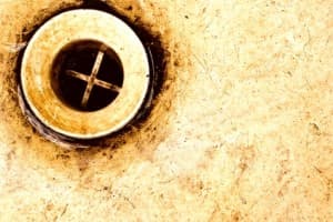 Close-up of a dirty drain opening, emphasizing the need for professional drain cleaning services to avoid the dangers of chemical cleaners.