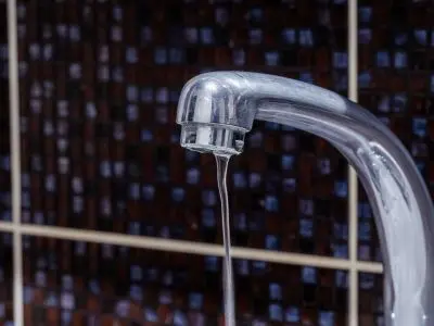 Faucet with low water pressure dripping water, highlighting plumbing issues in older homes.