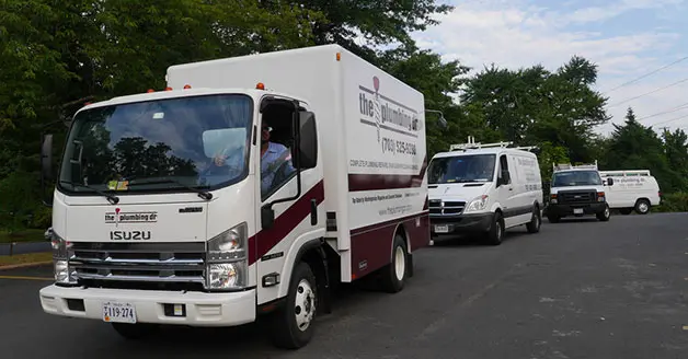 Plumbing service vehicles from The Plumbing Dr, including an Isuzu truck and various vans, parked in a row, emphasizing reliable plumbing solutions in Falls Church, VA.