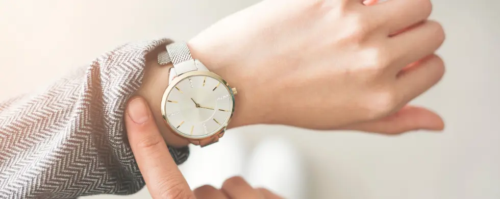 Person checking the time on a stylish watch while wearing a patterned sleeve, emphasizing punctuality and attention to detail.