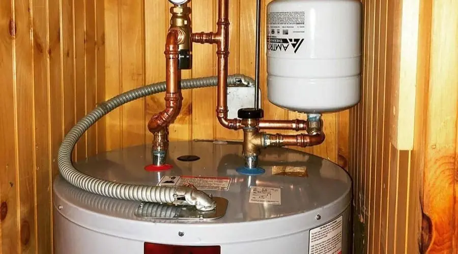 Water heater with copper and flexible piping, located in a wooden enclosure, illustrating essential plumbing maintenance for homeowners.