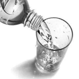 Pouring clean water from a bottle into a glass, emphasizing the importance of filtered water for health benefits and reducing contaminants.