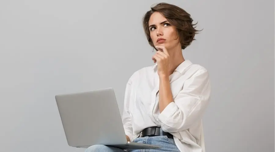 Person sitting with a laptop, thoughtfully considering plumbing advice and tips for home maintenance.