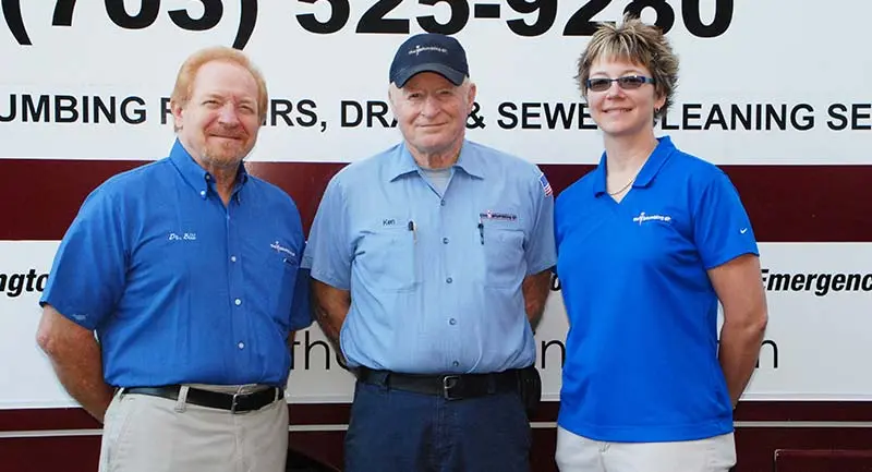 Three professional plumbers from The Plumbing Dr, wearing branded uniforms, standing in front of a service vehicle, emphasizing their commitment to quality plumbing services in Falls Church and Arlington, VA.