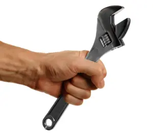Hand gripping an adjustable wrench, symbolizing plumbing repair tools relevant to addressing slab leaks.