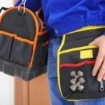 Plumber holding tool bags, showcasing essential equipment for industrial plumbing services.
